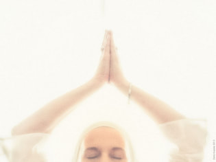 womans face and arms above head in prayer pose, white background